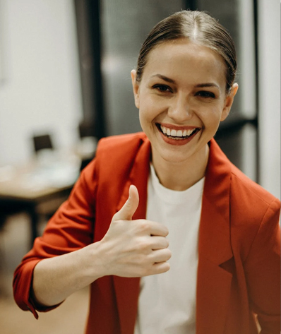 A woman smiling and giving a thumbs up
