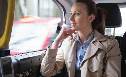 Professional woman pondering the ease of automated employee commute solutions while sitting in a vehicle.