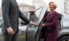 Smiling woman greeted by driver of a corporate car rental service